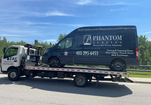 Zak Towing Service is transporting a Phantom Screens commercial van on a flatbed tow truck in Calgary, Alberta. The vehicle is securely loaded and professionally handled, highlighting reliable commerc...Sorry but this string is too long !!!
