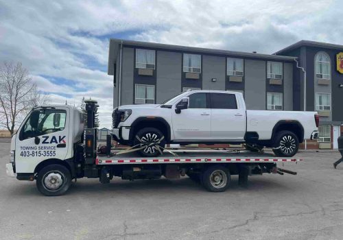 Zak Towing flatbed truck carrying a white Denali HD pickup in Calgary