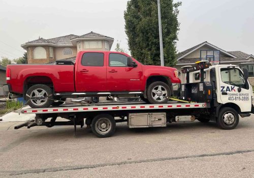Zak Towing safely transports a red GMC Sierra 2500 HD using a professional flatbed tow truck in Calgary. We provide fast, secure, and affordable towing services for pickups, SUVs, and all vehicle type...Sorry but this string is too long !!!