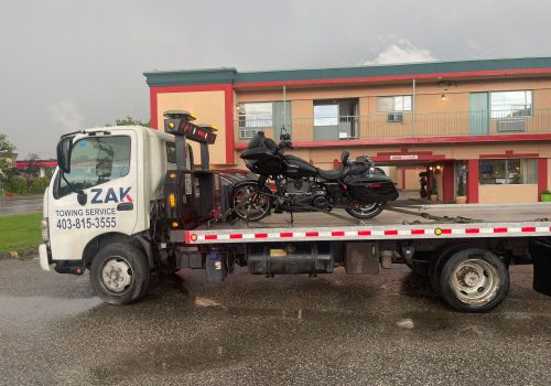 A Zak Towing flatbed tow truck is transporting a touring motorcycle in Calgary for a safe and secure motorcycle towing service.