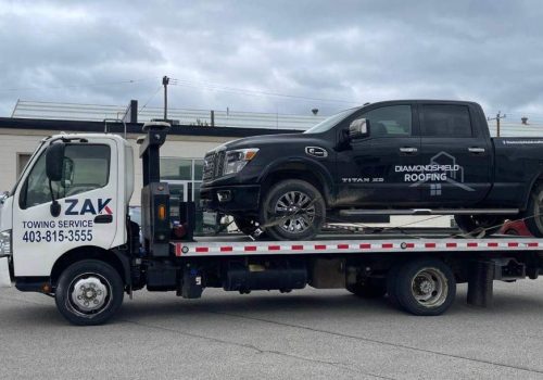 Zak Towing Service flatbed truck towing a black pickup in Calgary
